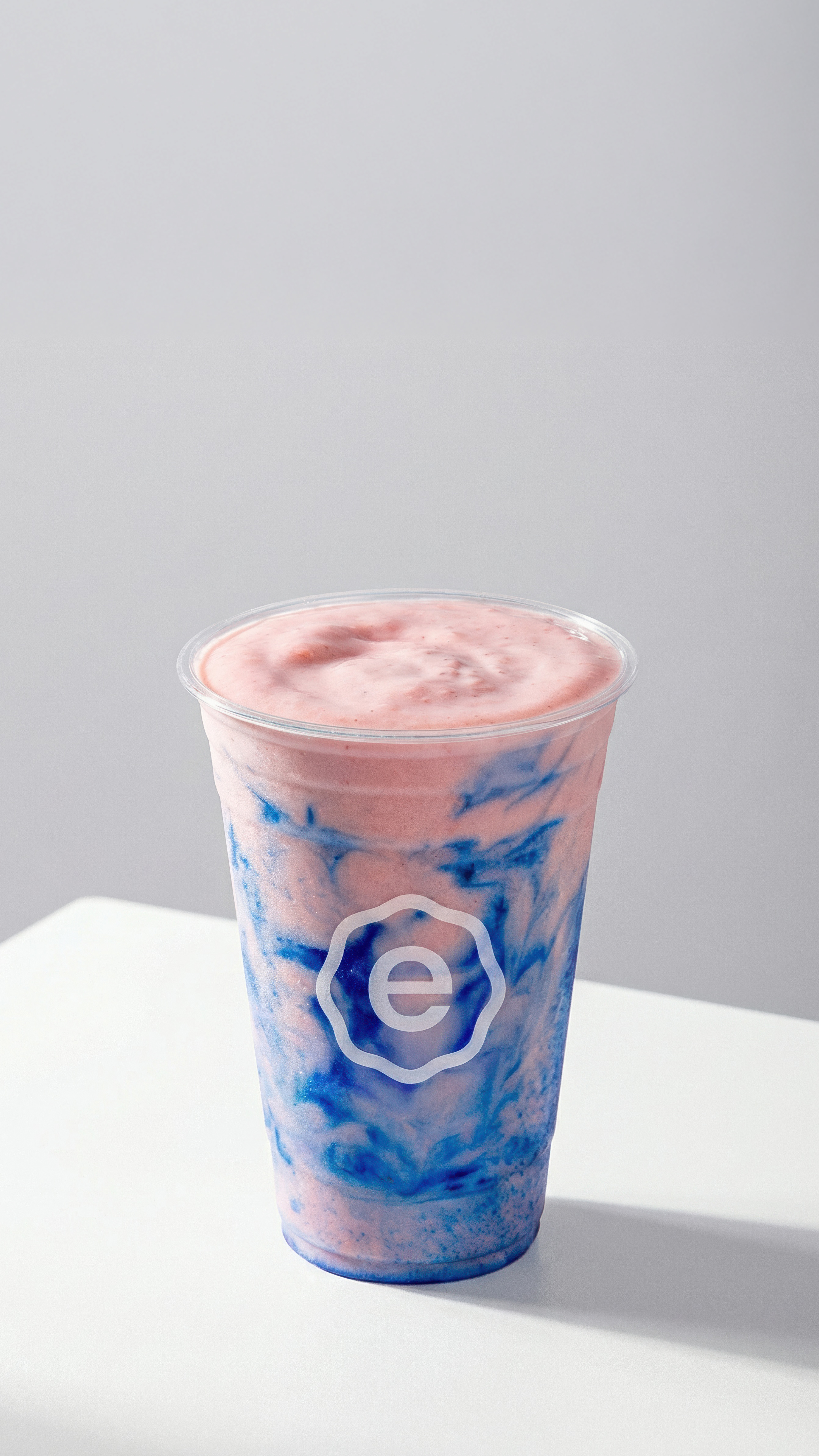 Pink and blue layered smoothie in a branded cup